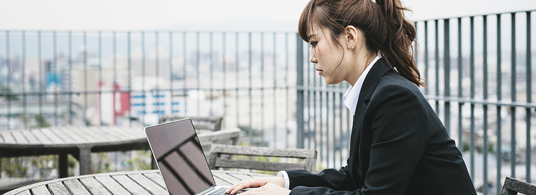Eine Frau in Kyoto, Japan, arbeitet draußen im Freien an einem Laptop